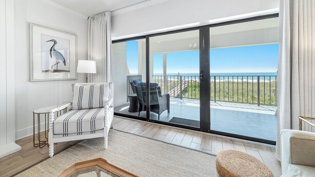 A balcony with a view of the beach and ocean.