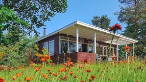 Ein Bungalow mit Veranda, umgeben von einem Blumenfeld.
