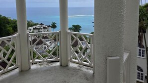 En balkon med havudsigt og en hvid bygning i baggrunden.