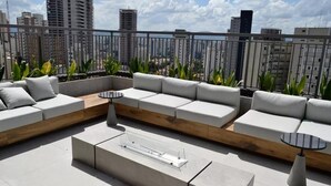 Una terraza en la azotea con un sofá modular, una mesa de centro y plantas en macetas.