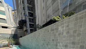Una piscina con paredes de azulejos y un muelle de madera, rodeada de edificios altos.