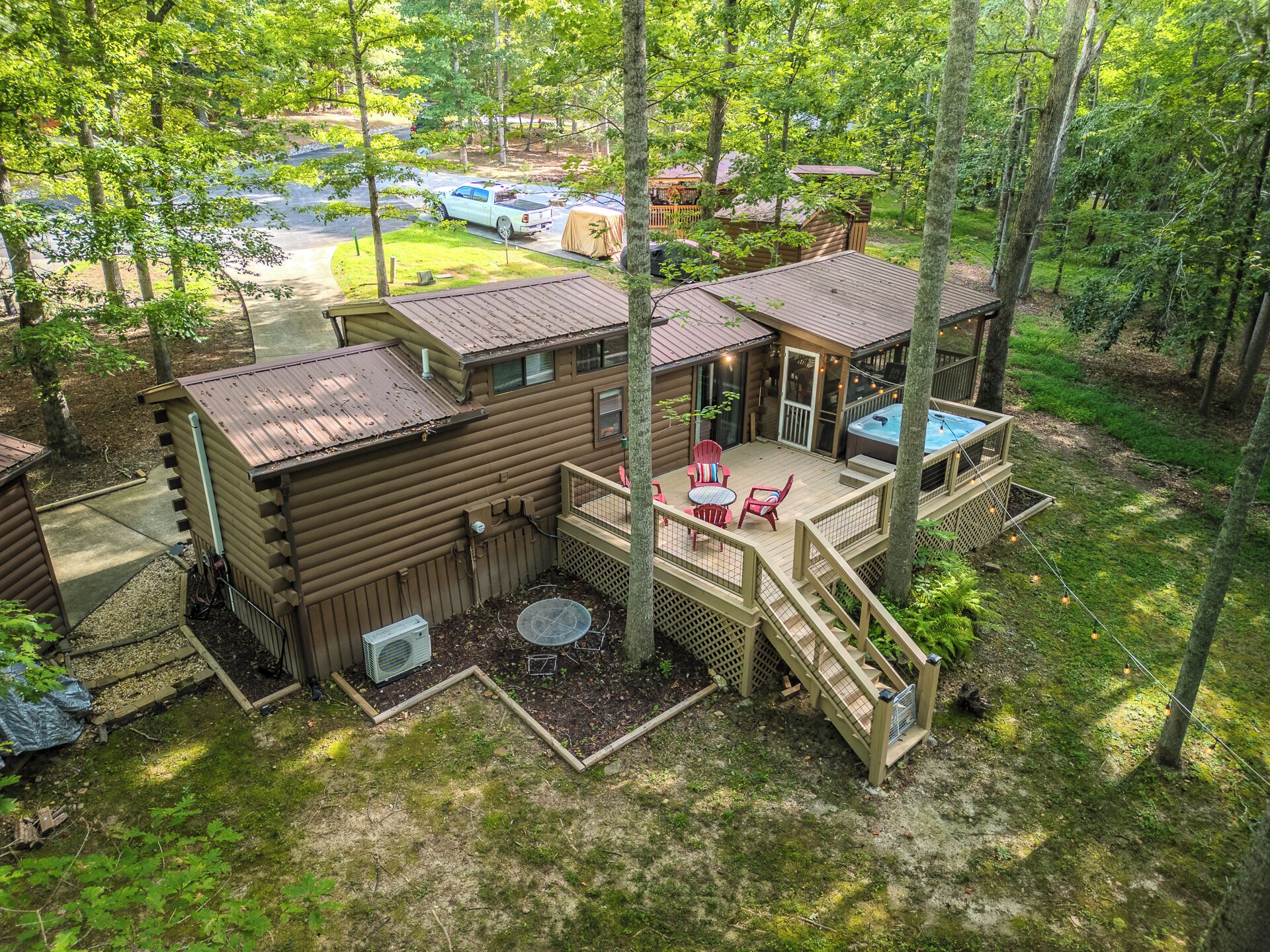 A cabin with a deck, outdoor seating, and a hot tub.