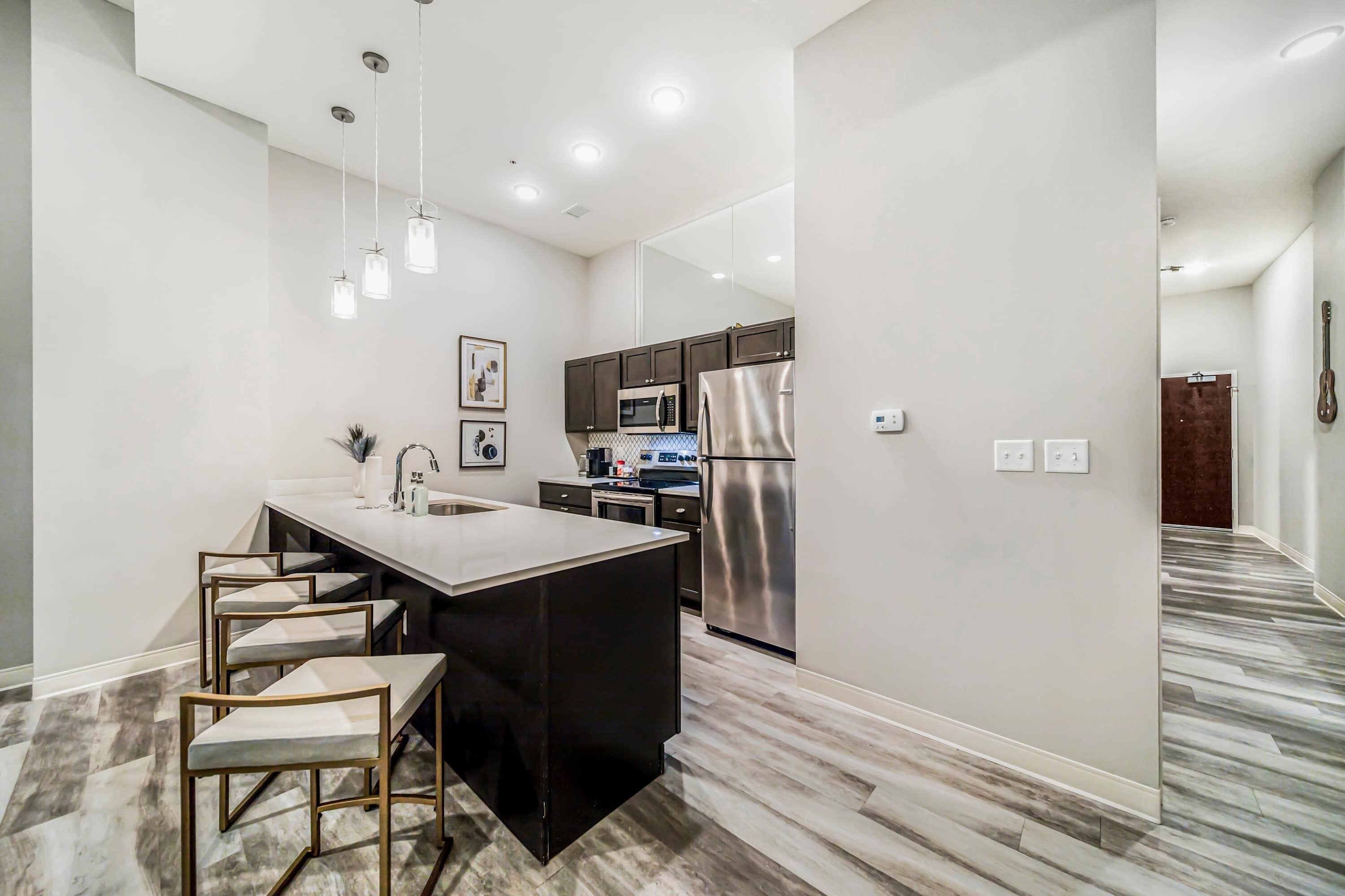A modern kitchen with a central island, stainless steel appliances, and pendant lighting.