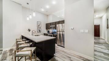 A modern kitchen with a central island, stainless steel appliances, and pendant lighting.