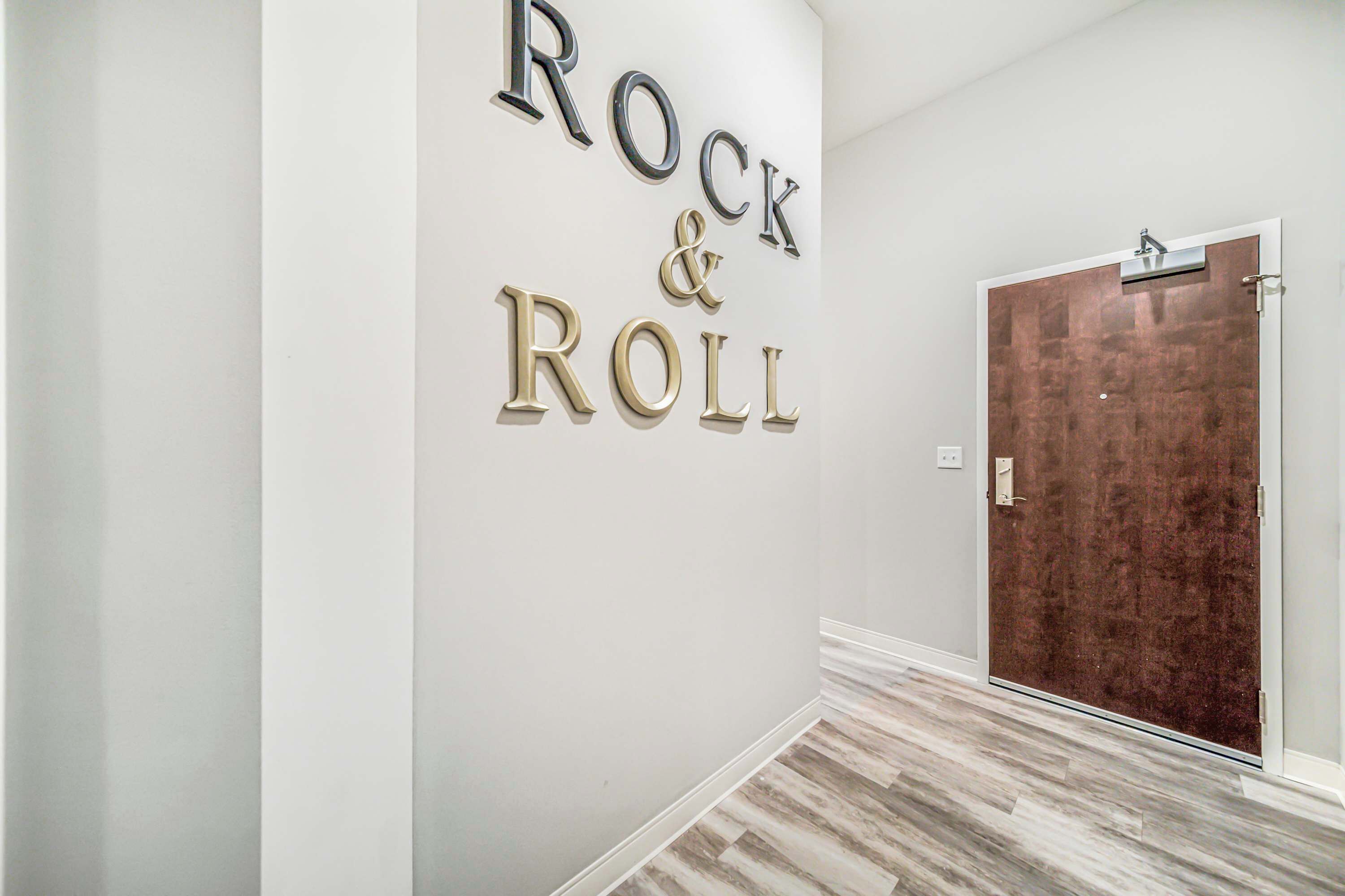Un pasillo con un letrero que dice "Rock & Roll" y una puerta de madera.