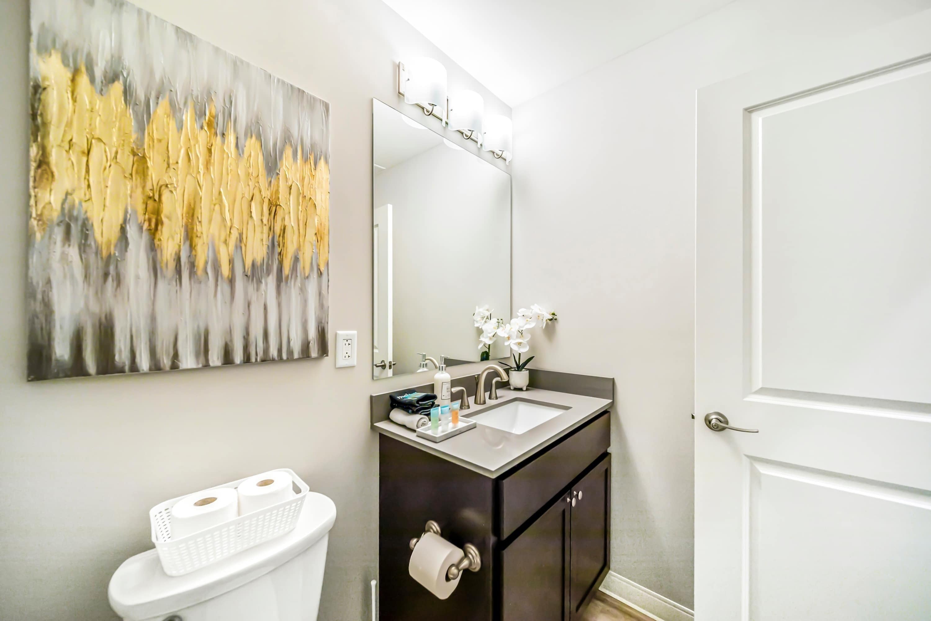 A bathroom with a white toilet, a dark vanity with a mirror, and a sink.