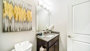 A bathroom with a white toilet, a dark vanity with a mirror, and a sink.