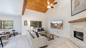 A spacious living room with a wooden ceiling, a fireplace, and a large TV mounted on the wall. - Scenic Location: Beautiful Townhome, 5 min to Base, Private Hot Tub, Walk to restaurants! (Park City)