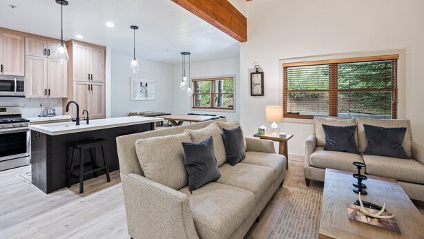 A modern kitchen with wooden cabinets, a central island, and pendant lighting. - Scenic Location: Beautiful Townhome, 5 min to Base, Private Hot Tub, Walk to restaurants! (Park City)