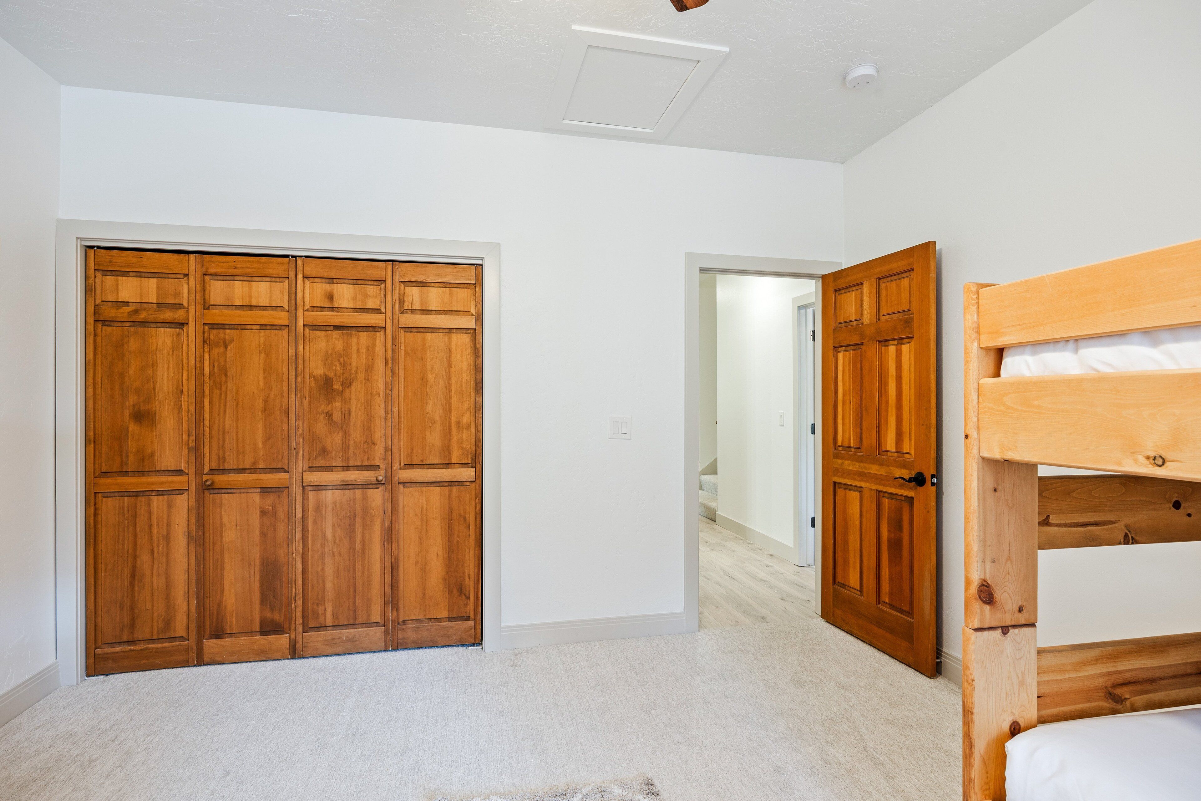 Une chambre avec une armoire en bois, un lit superposé et un plafond blanc.