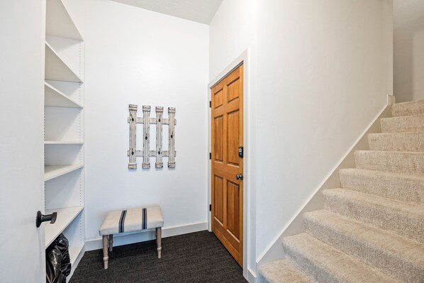 A hallway with a wooden door, a bench, and a staircase.