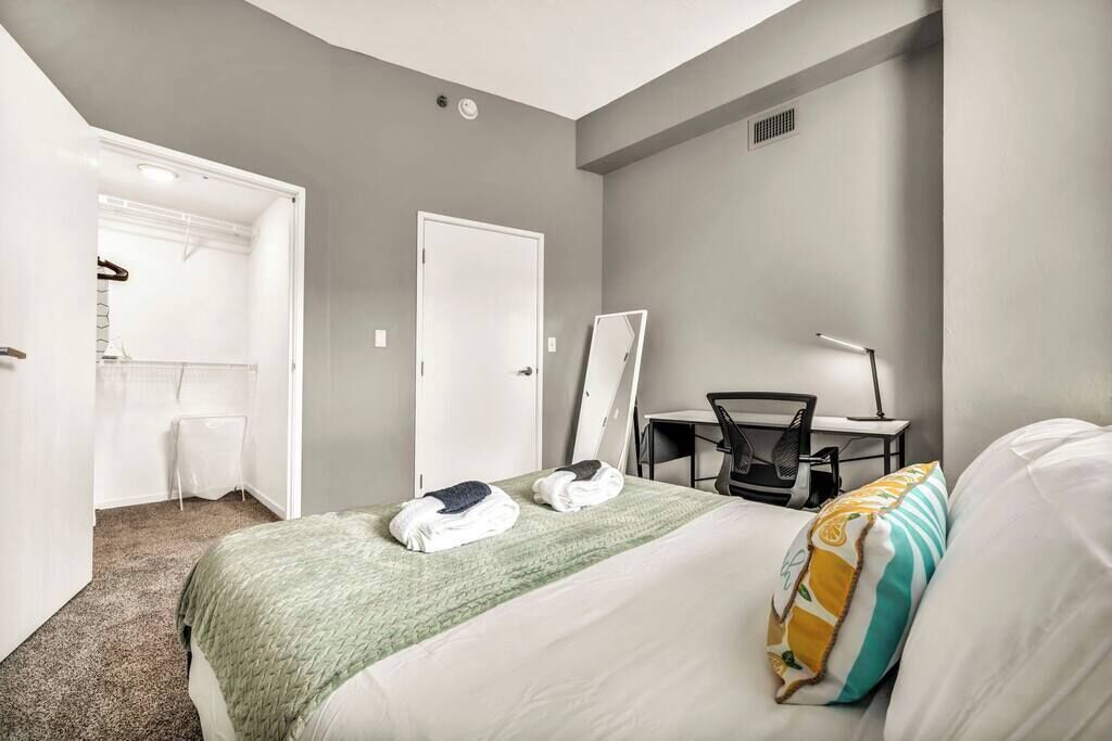 Ein Hotelzimmer mit Bett, Schreibtisch, Stuhl, Spiegel und Kleiderschrank.