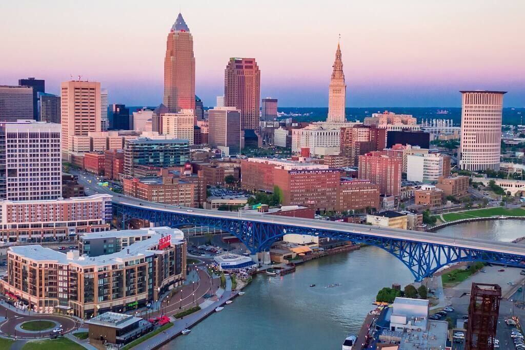 A cityscape with a prominent blue bridge over a river, surrounded by various buildings and a tall tower.
