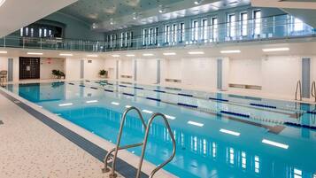 Una piscina interior con carriles bien definidos, un entrepiso con ventanas y suelo de baldosas.