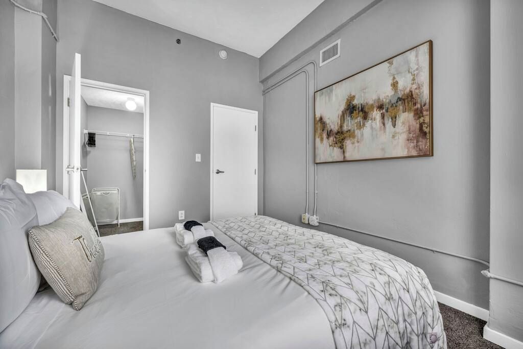 A hotel room with a bed, a shower, and a large abstract painting on the wall.
