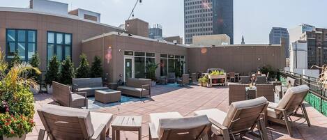 A rooftop patio with outdoor furniture, a pool, and city views.