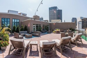 A rooftop patio with outdoor furniture, a pool, and city views.