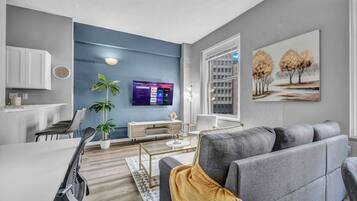 A modern living room with a grey sofa, a coffee table, and a TV mounted on the wall.