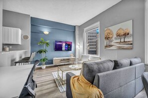 Una sala de estar moderna con un sofá gris, una mesa de centro y un televisor montado en la pared.