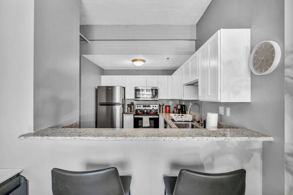 A modern kitchen with white cabinets, stainless steel appliances, and a granite countertop.