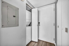 A hallway with a white door, a white wardrobe, and a built-in washing machine. - Modern 1B in Heart of Downtown • Pool & Spa • Gym (Cleveland)