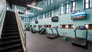 A gym with a staircase, treadmills, and exercise equipment.