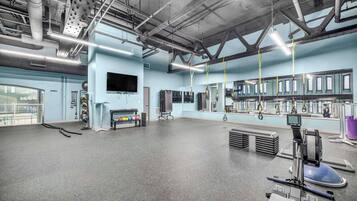 A spacious gym with exercise equipment, a large mirror, and a television on the wall.