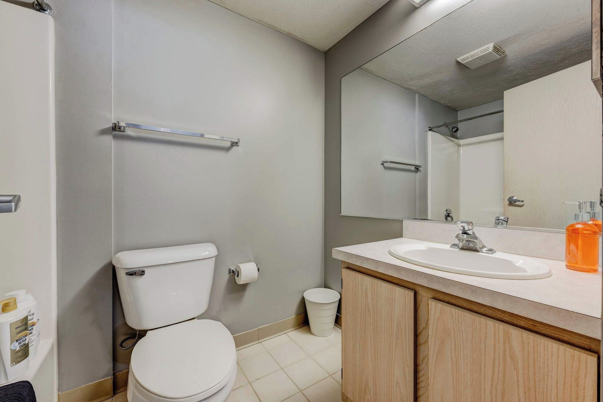 Een badkamer met toilet, wastafel, spiegel en prullenbak.