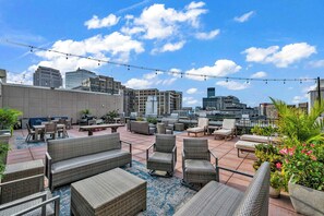 An outdoor patio area with wicker furniture, potted plants, and a city skyline in the background. - HUGE Loft in Heart of Downtown • Pool/Sauna • Gym (Cleveland)