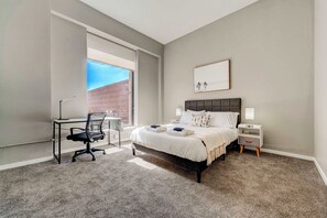 A bedroom with a bed, desk, chair, and a window. - HUGE Loft in Heart of Downtown • Pool/Sauna • Gym (Cleveland)