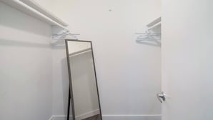 A bathroom with a white tiled wall, a mirror, and a door.