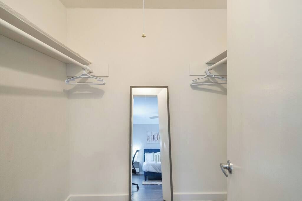 A narrow hallway with a mirror reflecting a bedroom.