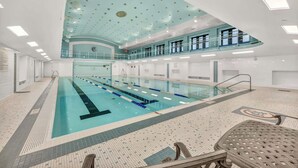 A large indoor swimming pool with multiple lanes, a glass ceiling, and a second level balcony. - Central Flat w/ Pool & Sauna • Gym•Heart of DT (Cleveland)