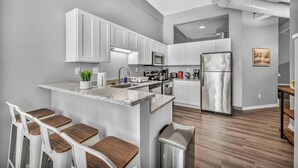 A modern kitchen with white cabinets, stainless steel appliances, and a central island with bar stools. - Huge Loft in Heart of Downtown • Pool & Spa • Gym (Cleveland)
