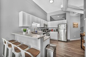 A modern kitchen with white cabinets, stainless steel appliances, and a central island with bar stools. - Huge Loft in Heart of Downtown • Pool & Spa • Gym (Cleveland)