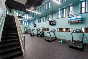 A gym with a staircase, treadmills, and exercise equipment. - Huge Loft in Heart of Downtown • Pool & Spa • Gym (Cleveland)