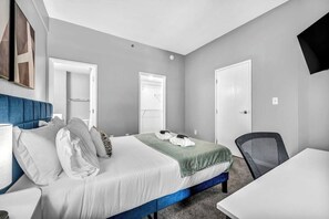 A hotel room with a bed, a desk, a chair, and a television.