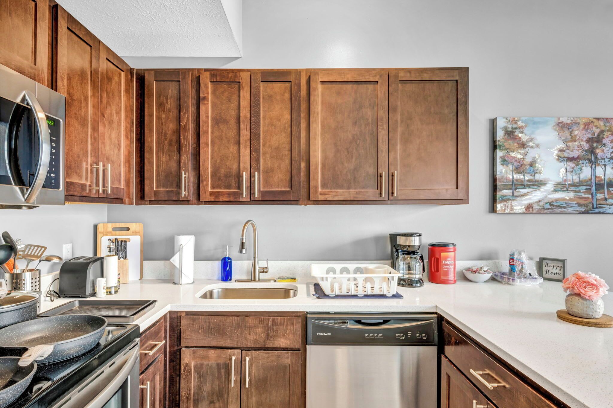 A modern kitchen with wooden cabinets, stainless steel appliances, and a white countertop.