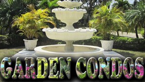 A multi-tiered fountain in a garden with lush greenery and palm trees.
