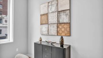 A room with a modern black console table, a decorative wall piece, and a window with a view of a building.
