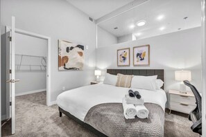 Een moderne hotelkamer met een groot bed, een nachtkastje, een stoel en kunst aan de muren.