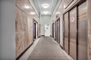 A hallway with marble walls, a carpeted floor, and elevators on both sides. - Central 1B in Heart of Downtown • Pool & Spa • Gym (Cleveland)
