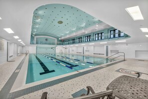 A large indoor swimming pool with multiple lanes, a second level viewing area, and a tiled floor. - Central 1B in Heart of Downtown • Pool & Spa • Gym (Cleveland)