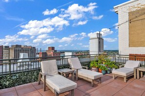 A rooftop terrace with lounge chairs, potted plants, and a city view. - Central 1B in Heart of Downtown • Pool & Spa • Gym (Cleveland)