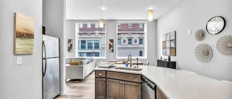 A modern kitchen with a large island, built-in appliances, and a view of the city.