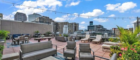 An outdoor patio area with wicker furniture, potted plants, and a cityscape view.
