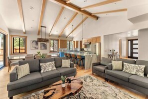 A spacious living area with two sofas, a coffee table, and a kitchen in the background.