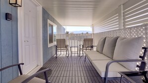 Un espacio al aire libre techado con sofá y sillones, una puerta y vistas a las montañas.