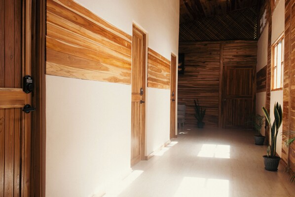 A hallway with wooden doors and walls, leading to a room with a sloped ceiling.