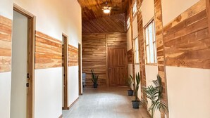 Un pasillo con paredes y techo de madera, plantas en macetas y una puerta al final.